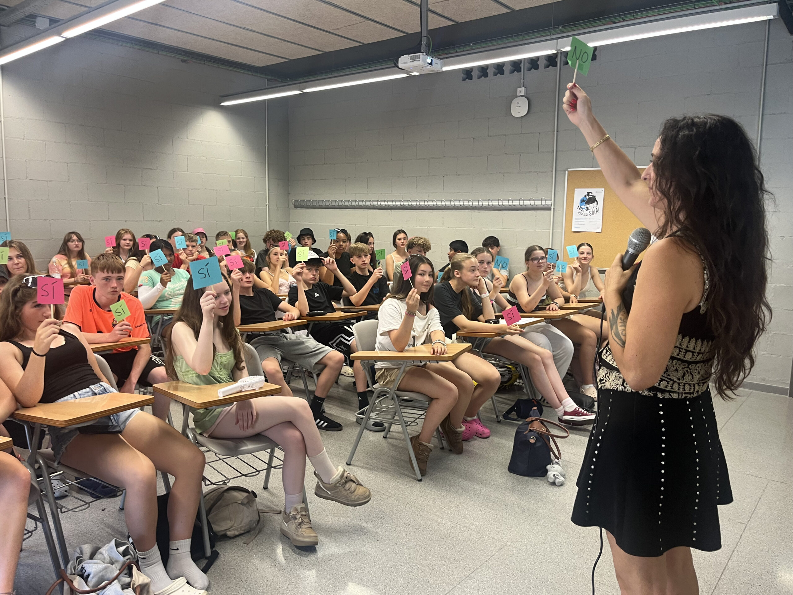 Maria holding up a sign to a classroom that is mimicking her.